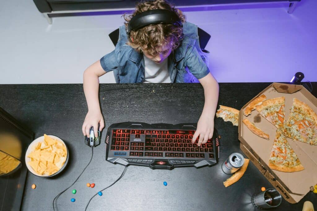 A Kid Wearing Headset Sitting at a Table Playing a Computer Game